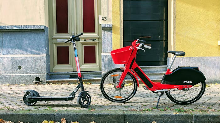 Una bici e uno scooter elettrico parcheggiati sul marciapiedi
